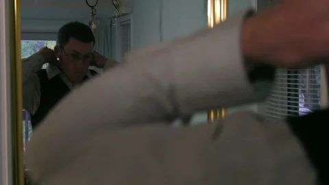 Groom getting ready in front of mirror adjusting collar and vest Stock Footage 88589254