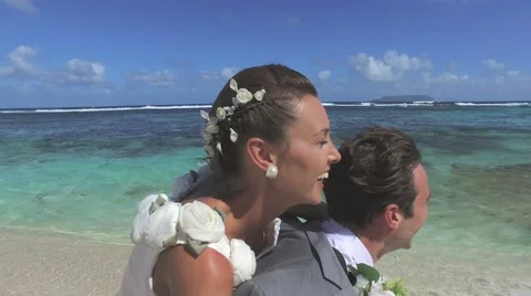 Groom giving piggyback ride to bride at the beach Vidéo 59188228
