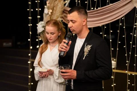 Groom giving a speech at a wedding reception with bride beside him Stock Photos