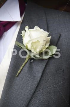 A Groom In A Grey Jacket And White Shirt, With A White Rose Boutonniere, In His