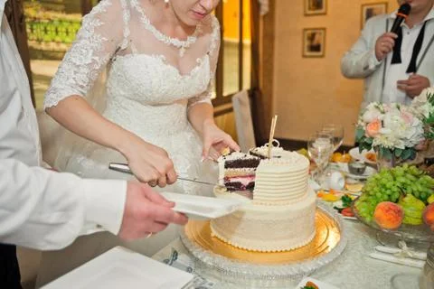 The groom helps the bride to divide the cake into pieces 521. Stock Photos