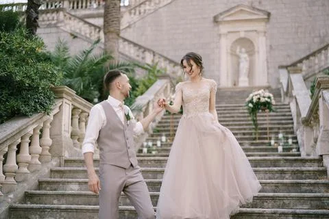 Groom helps bride down the stone steps Stock Photos