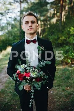 Groom holds bouquet Stock Photos
