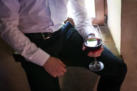 Groom holds in his hand a glass of red wine Stock Photos