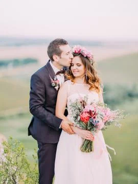 The groom is hugging the bride back while kissing on the forehead. Romantic Stock Photos