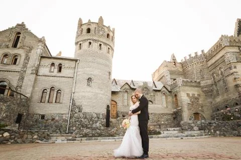 Groom hugging bride on the background of old building Stock Photos