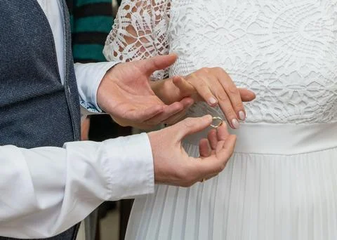 Groom placing ring on bride hand in close view. Symbol of marriage, love, c.. Stock-Fotos