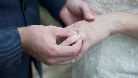 The groom puts the ring on the bride's finger, close-up of hands Stock Footage 239734330