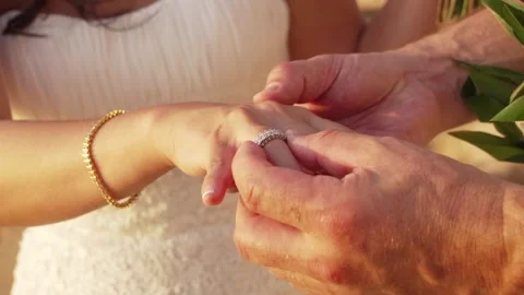 Groom puts silver wedding ring on brides hand during a beach wedding ceremony. Stock Footage 136268290