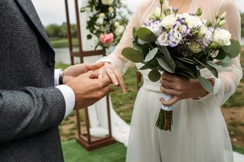 The groom puts the wedding ring on the bride's hand. Stock Photos