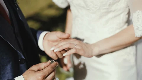 The groom puts the wedding ring on finger of the bride. marriage. hands with Stock Footage