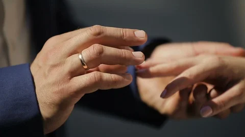 The groom puts the wedding ring on finger of the bride. Close up Stockbeeldmateriaal 96005127