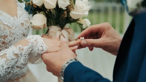 The groom puts the wedding ring on finger of the bride.  Stock Footage 114986483