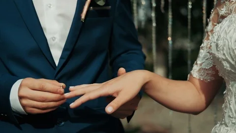 The groom puts the wedding ring on finger of the bride.  Stock Footage 114986580