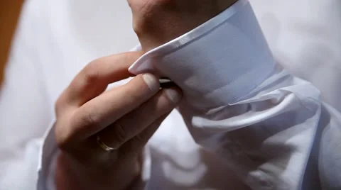 A groom putting on cuff-links as he gets dressed in formal wear .Groom's suit Vídeo Stock 64764470