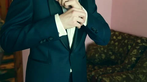 A groom putting on cuff-links as he gets dressed in formal wear .Groom's suit Video stock 64771504