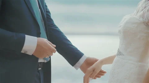 Groom putting a ring on brides finger at beautiful sea background. Close up Stock Footage 57816437
