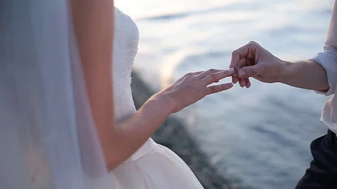 Groom putting a wedding ring on bride's finger Stock Footage 83119229