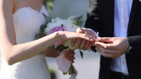 Groom putting wedding ring on brides finger close up summer day no face  Stock Footage 90927680