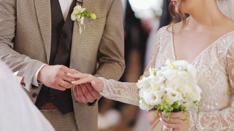The groom putting on the wedding ring on the finger of his bride's finger during Video stock 196003095