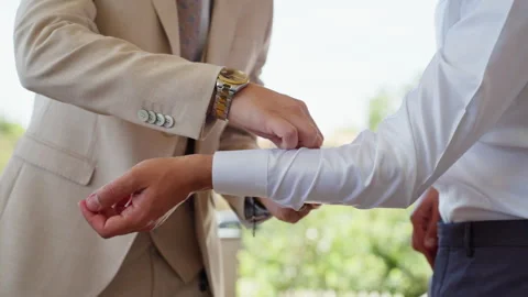 Groom Receiving Help With Cufflinks Outdoors Vidéo 327911204