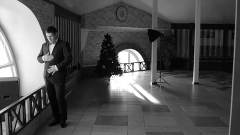 The groom standing at the window. A man adjusts his clothes. Black-and-white ima Vidéo 73635314