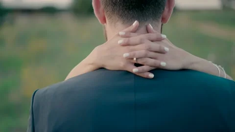 A groom stands with his back to the camera, a bride hugs the groom. Stock Footage 221921175
