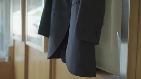 Groom suit jacket hanging in soft natural light Video stock 321517974