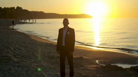 Groom walking on the beach during sunset Stock Footage 99551872