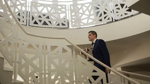 Groom walking to bride in gorgeous wedding dress on stairs indoors in restaurant Stock Footage 73781871