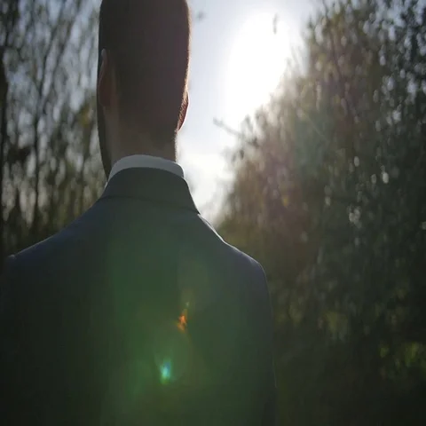 Groom walking spring park with trees close-up of shoulders and head shot slow Video stock 69483520