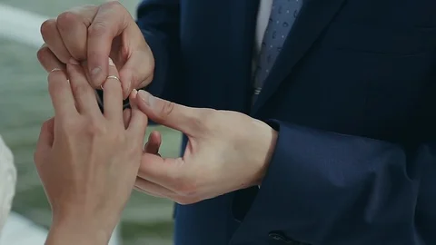 The groom wears a wedding ring on the bride's finger. Wedding ceremony near the Stock Footage 108486974