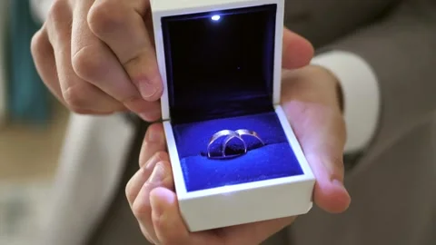 Groom's hands opening a box with wedding rings, beautifully lit Stock Footage 291540744