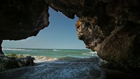 A grotto on the surf line, with the blue sky and skyline in the background. Long Stock Footage 217729940