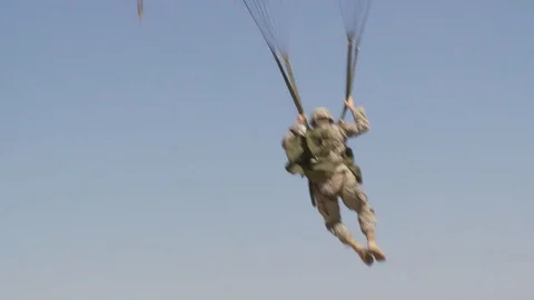 Ground angle view of paratroopers parachuting to earth. Stockbeeldmateriaal 74811974