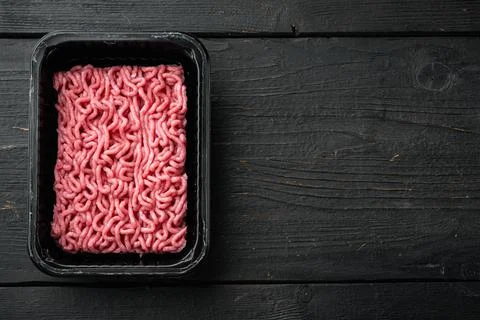 Ground beef meat in plastic tray, on black wooden table background, top view, Foto stock