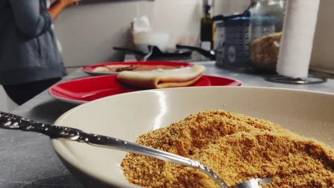 Ground biscuits with pancakes frying in the background 스톡 동영상 95656971