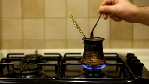 Ground black coffee in a copper Turk is brewed and boils on gas stove. Stock Footage 128017883