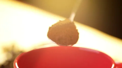 Ground coffee falling from spoon in cup on fresh roasted coffee beans background Stock Footage 153250247