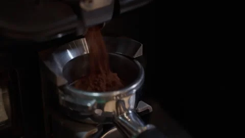 Ground coffee flows smoothly from grinder into portafilter Stockbeeldmateriaal 297352196