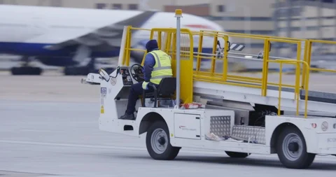 Ground crew driving baggage loading belt away from plane Stock Footage 114042171