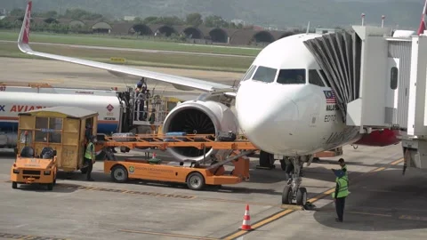 Ground crew guiding loading equipment, and baggage being prepared for departure. 動画素材 325655495
