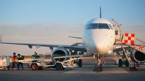 Ground Crew Loading Baggage onto White Regional Jet at Sunset on Tarmac. Stock Footage 337905373
