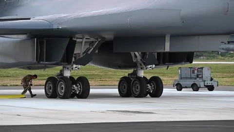 Ground crew positioning wheel chocks under B-1B Lancer's landing gear Stock Footage 300260974