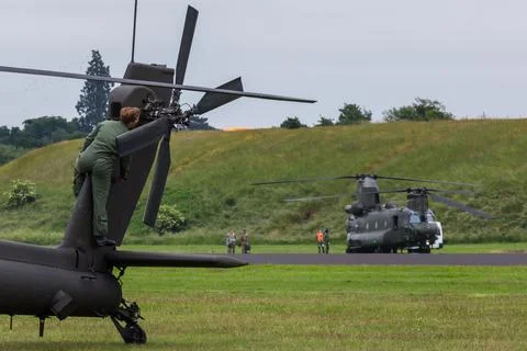 Ground crew prepare the Apache in front of the Chinook Stock Photos