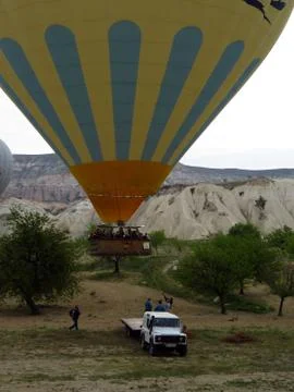 Ground Crew Pulling Down a Landing Yellow and Blue Hot Air Balloon Stock Photos