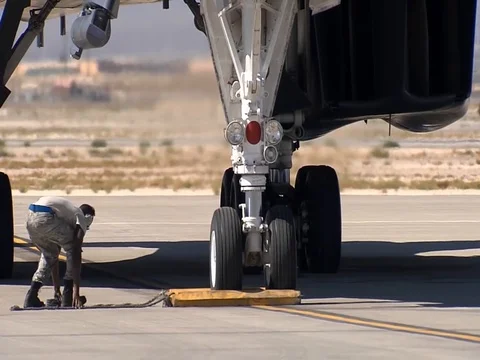 Ground crew removing wheel chocks B1 Bomber landing gear Stock Footage 106987292
