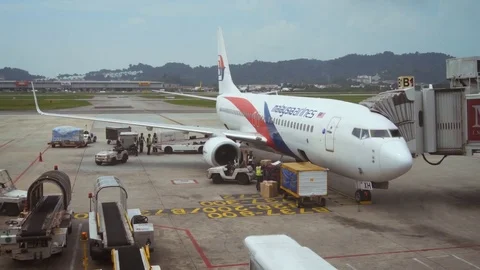 Ground crew servicing recently arrived Malaysia Airlines passenger jet Stock Footage 77140283
