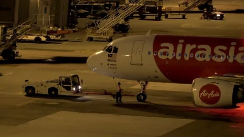 A ground crew walks beside airplane being pushed back prior to takeoff Stock-Footage 106947657