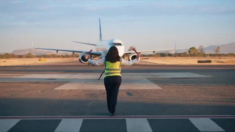 Ground Crew Worker Guides Aircraft to Airport Gate During Golden Hour. Stock Footage 337913463